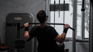 A man working out on a lat pulldown machine in a gym, focusing on strength building.