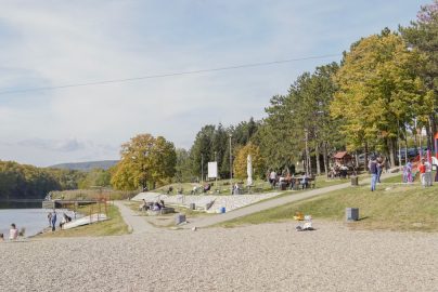 A peaceful park scene with riverside path, trees, and playground, perfect for a family outing.